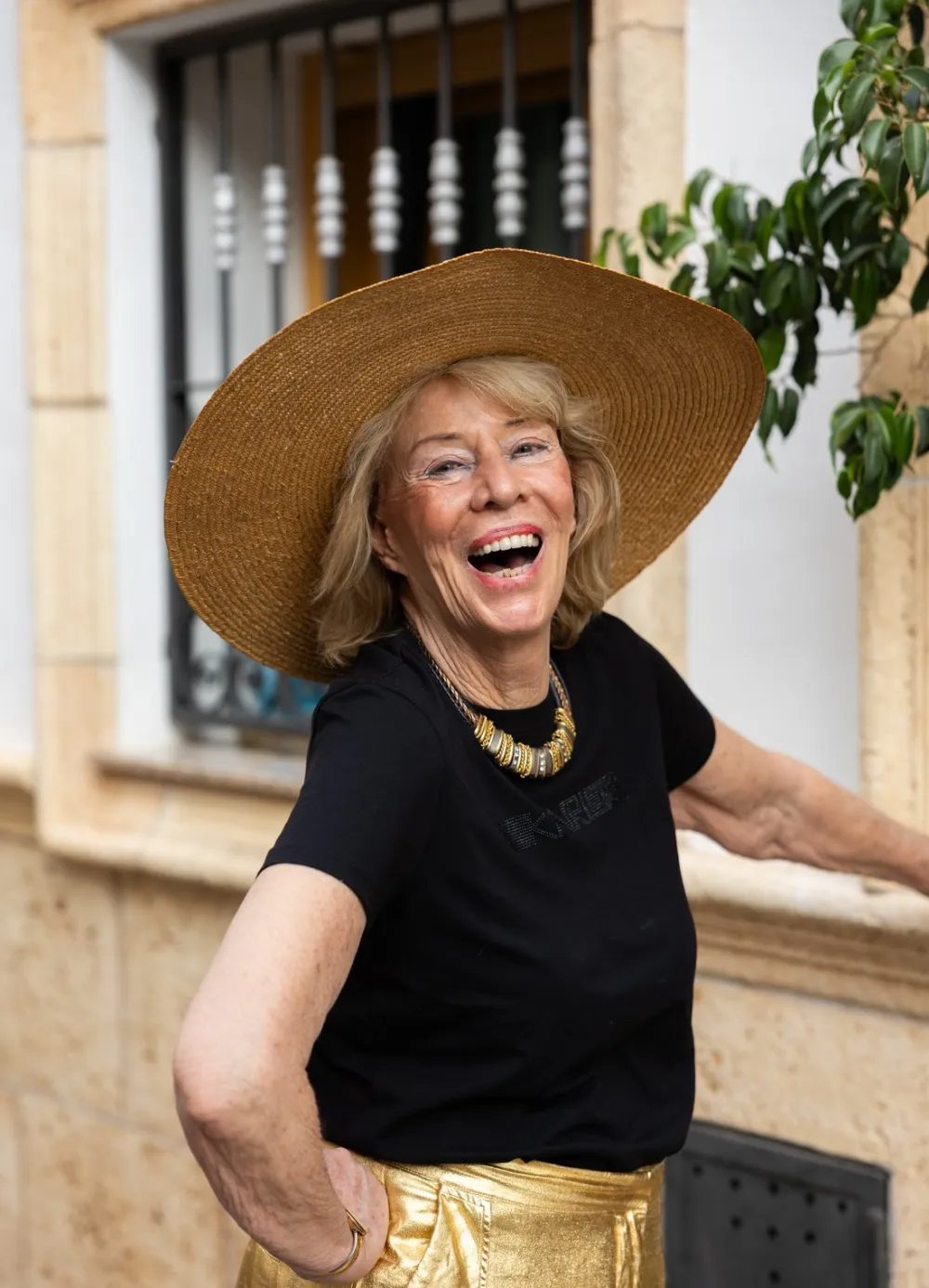 Jessica Larive lacht, met een strohoed, in een Spaans straatje